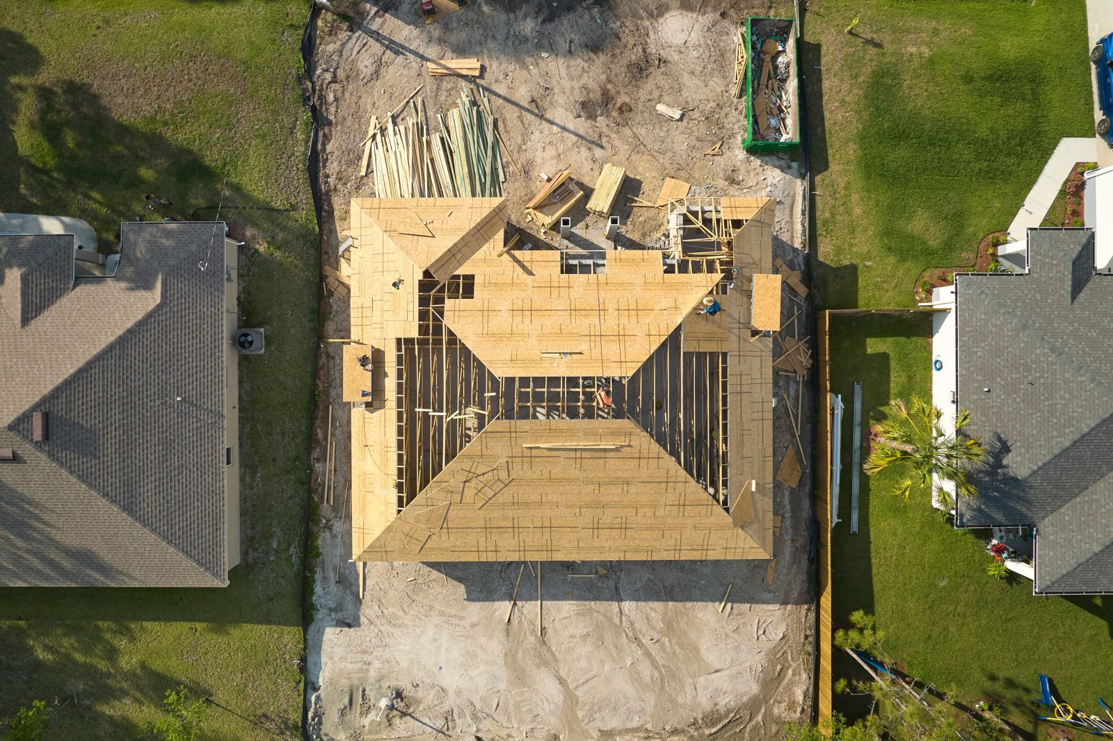 Aerial view of a house under construction with its wooden roof frame in place